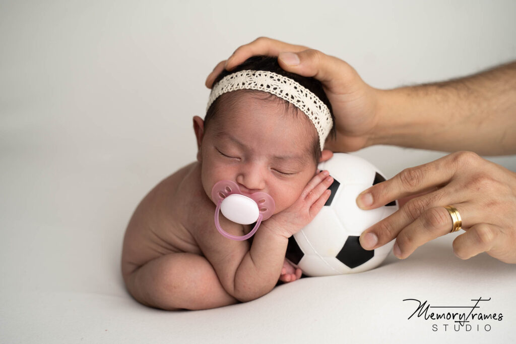 baby posed by kitchener newborn photographer for phootshoot with a ball